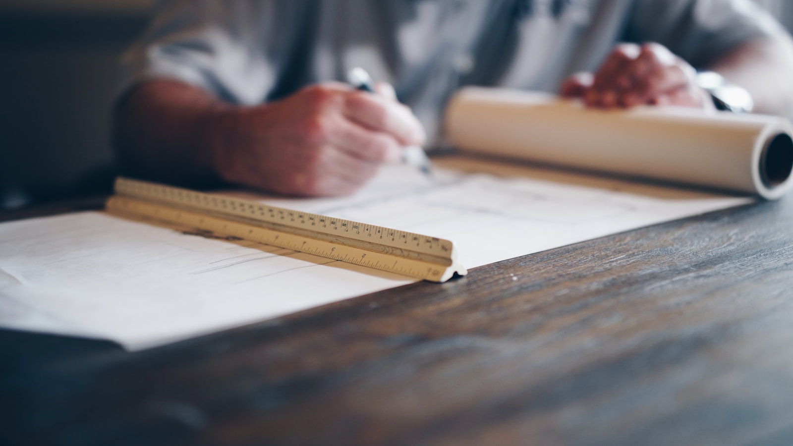 Designer drafting a plan with a ruler and pencil